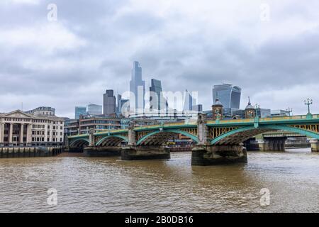 Iconic CIty of London skyscrapers and skyline of the financial district viewed over Southwark Bridge in cloudy wet weather in winter Stock Photo