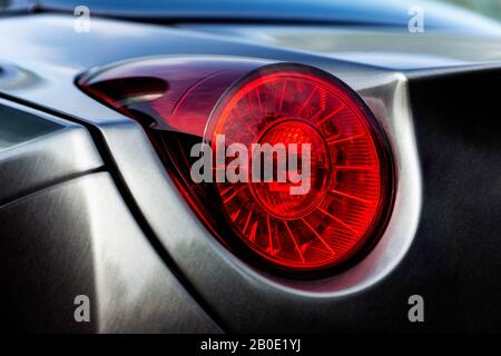 Detail of the rear end of a silver car with focus on the taillight. Stock Photo