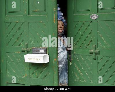 Mittenwald, Germany. 20th Feb, 2020. The pre-dancer of the Mittenwald jingles looks through a door before the traditional carnival procession. With their bells the bell stirrers ring in the spring in Upper Bavaria. Credit: Angelika Warmuth/dpa/Alamy Live News Stock Photo