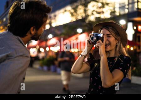 Young woman taking picture of young man on street Stock Photo