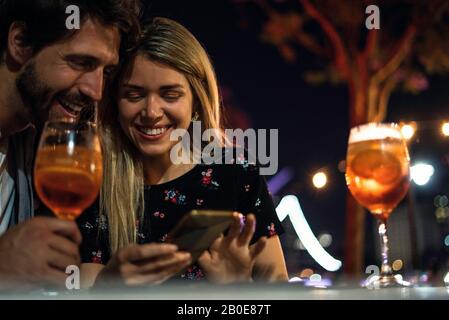 Young couple using smart phone at outdoor cafe Stock Photo