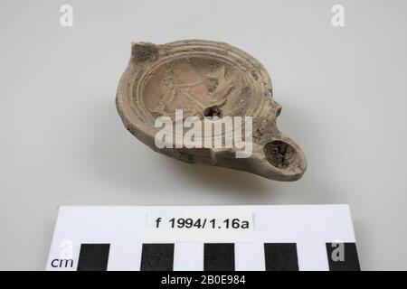 Terracotta oil lamp, decorated, with spout, filler hole and fire hole. The ear is missing, caked earth in and on the oil lamp., Oil lamp, earthenware, terracotta, 8.5 x 6.1 x 3 cm, roman, Netherlands, Utrecht, Bunnik, Fighting Stock Photo
