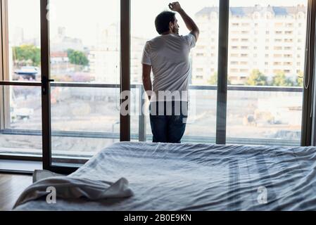 Young man standing by the window Stock Photo
