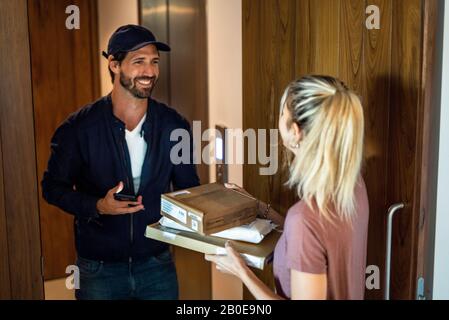 Young woman receiving parcels from delivery man Stock Photo