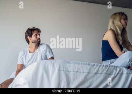 Upset couple sitting on bed Stock Photo