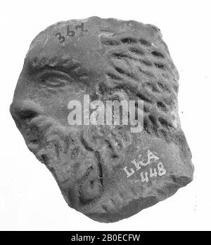 Fragment of a brown-burned oil lamp. The concave mirror is decorated with a relief image of a head of a bearded man 'and profile'., Oil lamp, earthenware, terracotta, 0.8 x 4.1 x 3.5 cm, 1st and 2nd century AD. 1-200, Turkey Stock Photo