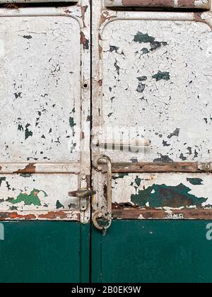 Paint peeling off the rusty metal surface of some old doors - background - texture Stock Photo
