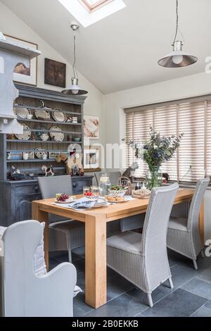 Pendant lights and closed Venetian blinds with wooden table and kitchen dresser Stock Photo