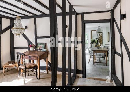 Early 19th century crystal chandelier above traditional French school desk with ebonized side chair. Stock Photo