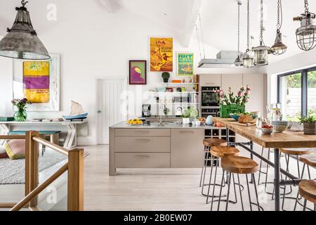 Reclaimed lights above breakfast bar with 1960s style artwork in open plan kitchen renovation Stock Photo