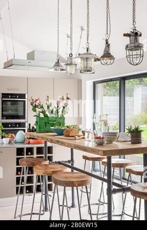 Reclaimed lights above breakfast bar in open plan kitchen Stock Photo