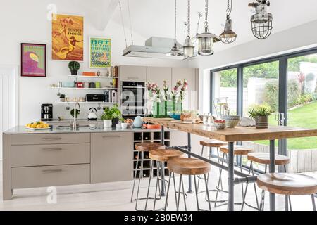 Reclaimed lights above breakfast bar with 1960s style artwork in open plan kitchen renovation Stock Photo