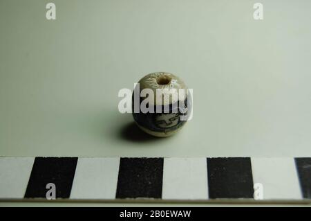 bead, mask, facial bead of white opaque glass with an opaque dark blue frieze surrounded by four faces, the details are in dark purple glass. Probably the faces represent a mask of Medusa, where the blocks around the face represent the snakes of Medusa., Bead, glass, diam. 1.5 cm, 1st Century, Egypt Stock Photo