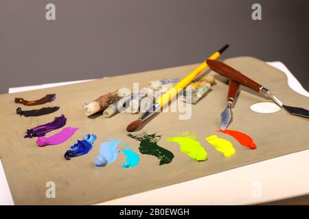 Oil painting. Palette with paints and brushes. The main tools of artist brush and palette knife. Squeeze out oil paints on a palette Stock Photo