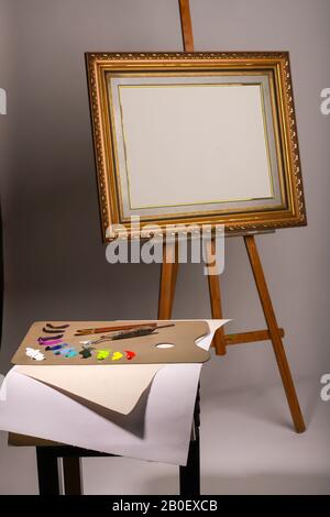 Oil painting. Easel and blank canvas. Palette with paints and