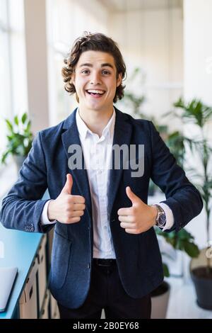 business and office concept - handsome buisnessman with jacket over shoulder showing thumbs up Stock Photo