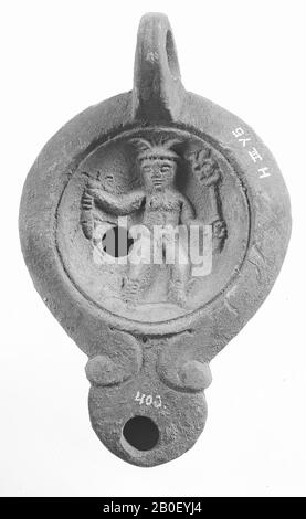 A red-nested lamp with an oval body on a recessed, round base. The concave mirror is surrounded by a recessed circle and decorated with a relief of Hermes with an indistinct object in one, a caduceus in the other hand. The short, broad spout with a small fire hole is decorated with volutes and round closed. The small filling hole is to the left of the figure. The vertically attached ear is decorated with notches. Brand: CCLO.SVC. and an in relief, oil lamp, pottery, terracotta, 4.6 x 11.6 x 7.3 cm, 1st and 2nd century AD. 1-200, Africa Stock Photo