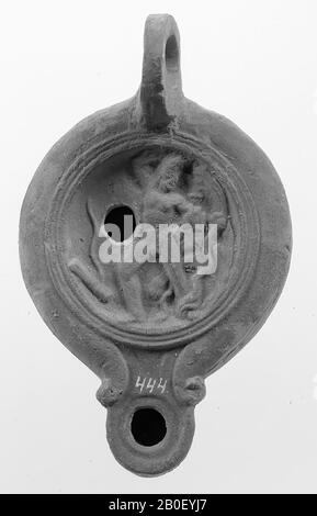 A red-nested lamp with an oval body on a flat, round base. The concave mirror is surrounded by concentric circles and decorated with a relief of Heracles wrestling with the hydra. An unclear object is to the left of the figure. The short, narrow spout with a small fire hole is rounded off and decorated with volutes. The small filling hole is to the left of the figure. The vertically attached ear is ring-shaped and decorated with notches. Brand: HERMAT, oil lamp, pottery, terracotta, 4.1 x 10.2 x 6.1 cm, 1st and 2nd century AD. 1-200, Italy Stock Photo