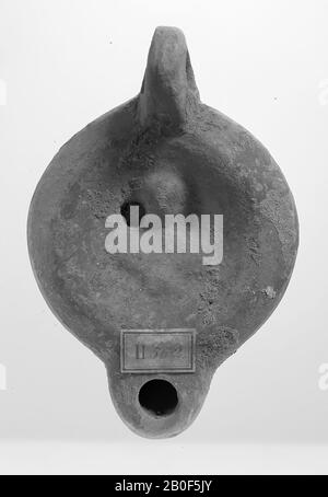 A red-bristling light bulb with a round body on a round base. The hollow, round mirror is surrounded by concentric circles and decorated with a Lunabust. The small filling hole is to the left of the figure. The short, flat spout is round and has a large fire hole. The vertically attached ear is decorated with notches. The spout of the spout is heart-shaped. Brand: recessed sole, oil lamp, earthenware, terracotta, 4.7 x 10.7 x 7.3 cm, 2nd half 1st century to 1st half 3rd century AD. 50-250 AD, Tunisia Stock Photo