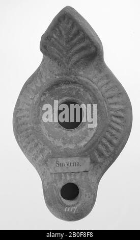 A lamp of red earthenware with an oval-shaped body on a round base. The round, flat mirror is surrounded by a relief edge with the large filling hole in the middle. The shoulder runs diagonally and is ribbed. The short, rounded, rounded spout has a small fire hole and is ribbed. The vertically set handle is delta-shaped with a leaf ornament and decorated with notches on the underside, as well as the spout, oil lamp, earthenware, terracotta, 3.7 x 10.7 x 6.4 cm, 3rd and 4th century AD. 200-400, Turkey Stock Photo