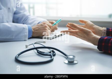 medical consultation - patient in clinic office asks the doctor for advice. focus on woman hands Stock Photo