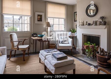 Upholstered armchair by Stephen Pardy with footstools for extra seating at windows in Georgian townhouse. Stock Photo