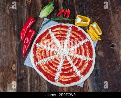 Close-up of Italian pizza preparation. Spreading tomato sauce on pizza dough and preparing for baking with other ingredients. Stock Photo