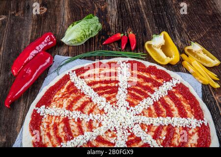 Close-up of Italian pizza preparation. Spreading tomato sauce on pizza dough and preparing for baking with other ingredients. Stock Photo