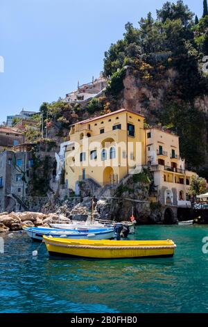 Small, colourful boats at anchor in a quiet cove along the Amalfi Coast, Italy Stock Photo