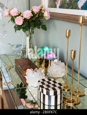 Gold candlesticks and cut flowers with jewellery boxes on cabinet Stock Photo