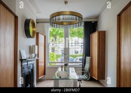 Clare Turner wall-hung cupboards in American walnut with Columbo lamp on mantlepiece, vintage Array lamp on desk  and  circular ceiling light Solaris, Stock Photo