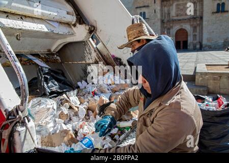 Oaxaca, Mexico - Garbage collectors sort recyclable materials from other trash at the back of a garbage truck. Stock Photo