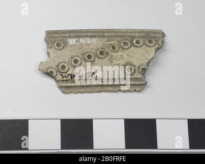 Fragment of a one-sided three-layer comb: part of the middle section of a handle blade. Type: long comb. Decoration: handle leaf: dot circles forming a horizontal S and lines running parallel to the edges. Shape: straight base, slightly curved top. Tooth plates: 0. End plates: 0. Teeth: 0. Rivets: 0. Thin handle blade. Saw marks: So first the teeth plates and the handle blades have been attached to each other and then the teeth sawn in., Comb fragment, organic, antlers, l = 4.2 cm and b = 2.1 cm., Vmec 800-900 Stock Photo