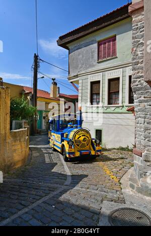 Kavala, Greece - June 11, 2018: Tourist train driving through narrow street in Panagian district in the city in East Macedonia