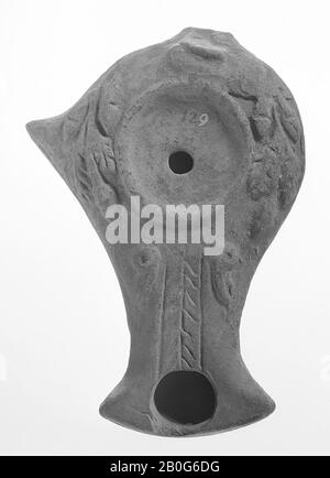 A gray-varnished oil lamp with a round, flat body on a round, low pedestal. The mirror is surrounded by a raised edge with a very small filling hole in the middle. The long spout is angled and decorated with a leaf motif and bird heads. On the shoulder, which is decorated with a leaf motif, there is a pointed scrub on the left, oil lamp, earthenware, terracotta, 3 x 10 x 7.3 cm, 1st century BC. -100 Stock Photo