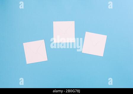Three white sheets of paper on a blue background. Empty cardboard envelopes for text Stock Photo
