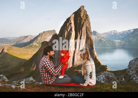 Travel family mother and father with baby outdoor camping healthy lifestyle Segla mountain view sustainable tourism in Norway man and woman with child Stock Photo