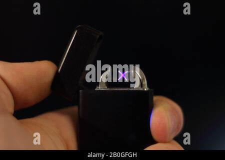 hand holding a plasma lighter in front of a black background Stock Photo