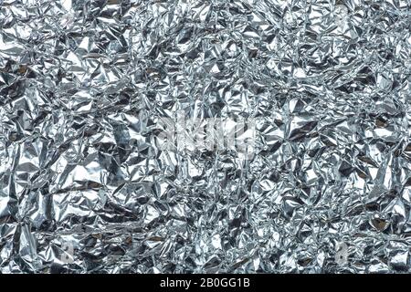 Crumpled foil background. The texture of crumpled iron aluminum foil reflective color. Copy space. Stock Photo