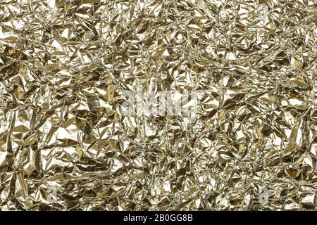 Crumpled foil background. The texture of crumpled iron aluminum gold reflective color. Copy space. Stock Photo