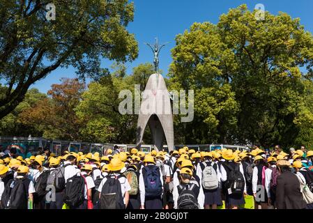 Remembering child victims of the Atomic Bomb, schoolchildren pay their respects at the Children's Peace Monument, Peace Memorial Park, Hiroshima, Stock Photo