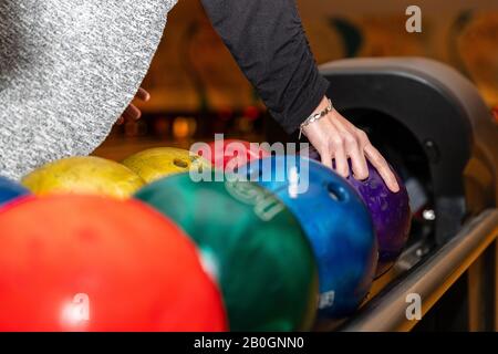 Hand picking up bowling ball at bowling alley. Stock Photo