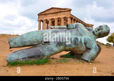 Statue of fallen Icarus in bronze in front of the 2,400 year old Temple of Concordia, one of the best preserved Ancient Greek Temples at Agrigento, Th Stock Photo