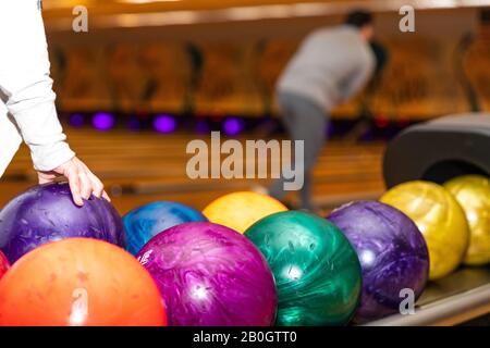 Hand picking up bowling ball at bowling alley. Stock Photo