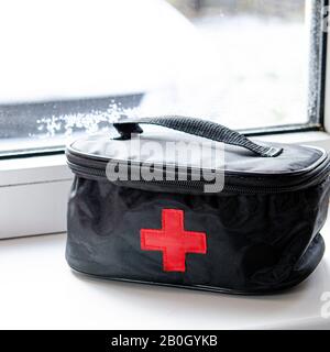 Car first aid kit with a set of medicines to save the life of the driver and passengers stands on a window sill Stock Photo