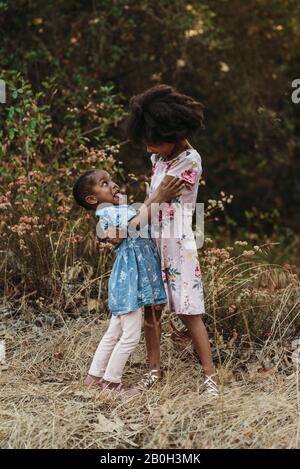 Two sisters laughing and smiling at each other in field Stock Photo