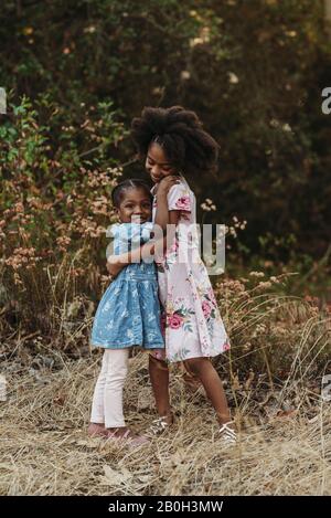 Portrait of two sisters hugging in backlit field Stock Photo