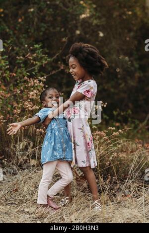 Two sisters laughing and smiling at each other in field Stock Photo