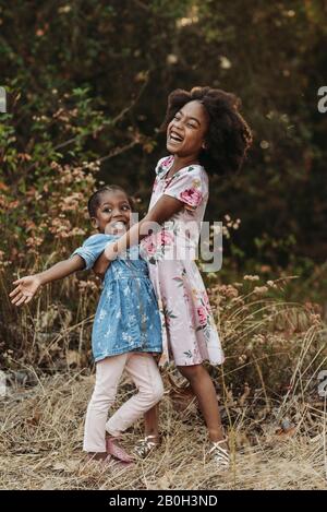 Two sisters laughing and smiling at each other in field Stock Photo