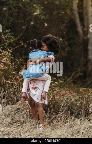 Portrait of two sisters hugging in backlit field Stock Photo